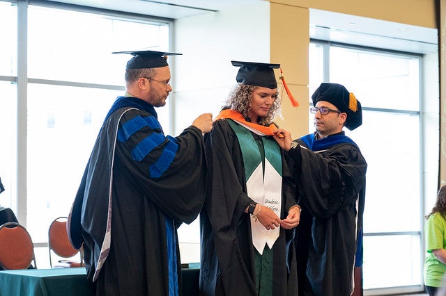 master's student being hooded by advisor