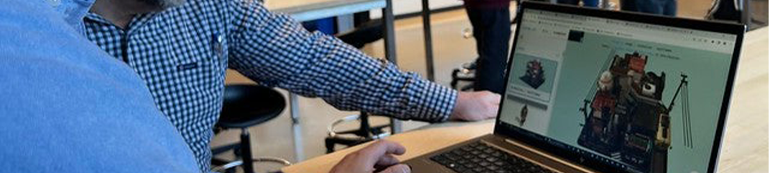 Two male professors looking at a laptop in a classroom.