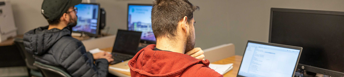 Two male students listening to a lecture in a classroom.