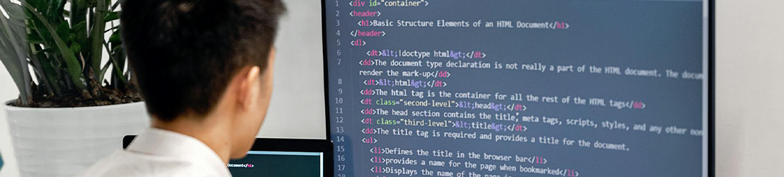 A male student coding on a computer monitor.