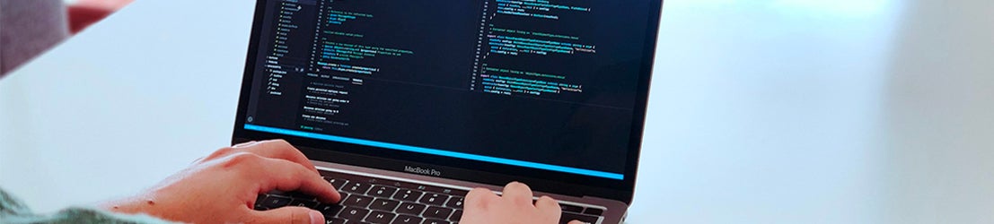 A student typing code on a laptop computer.