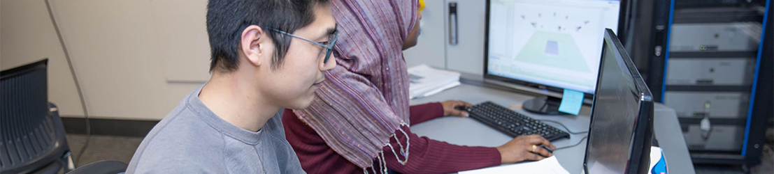 Two students working on computers in a lab.