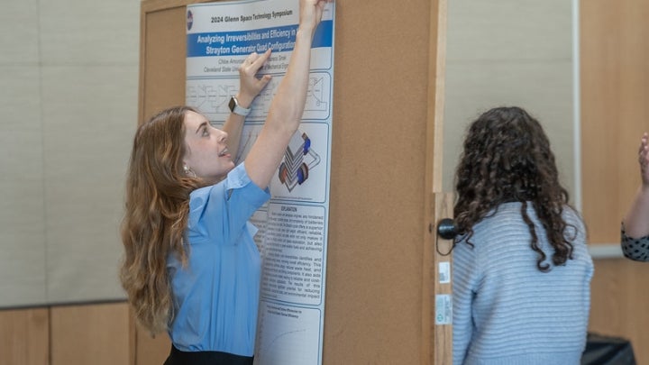 Student hanging up research poster