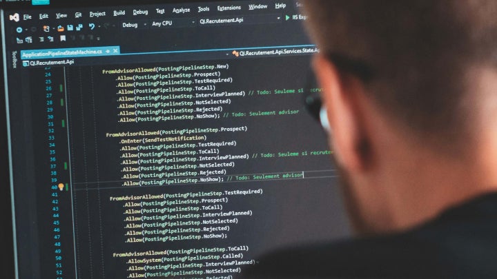 A male student working on code on a computer monitor.
