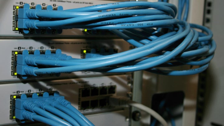 Multiple blue cables connecting into a network router.