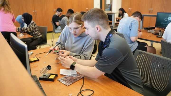 Two students discussing soldering techniques during the workshop