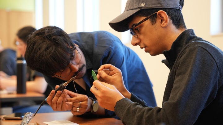 two students working on a soldering project during the Soldering Workshop