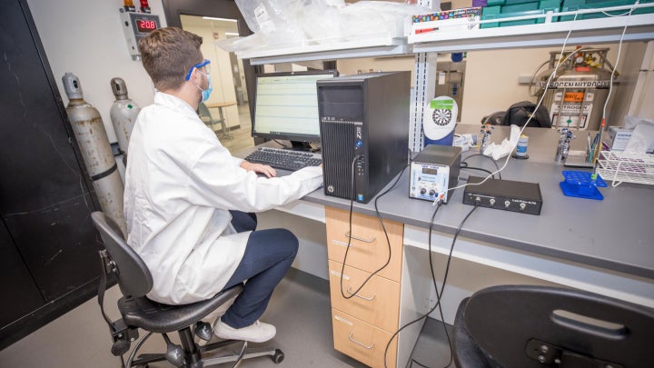 A research student typing on a computer in a lab.