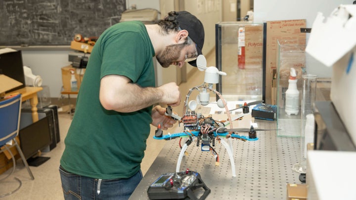 A student working on a drone in a classroom.