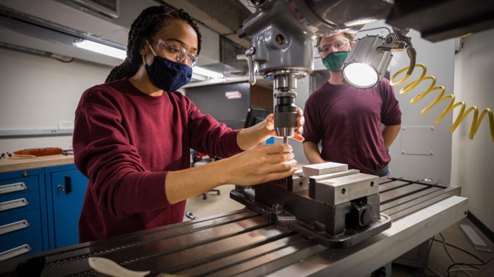 Two mechanical engineering students working with research equipment in a lab.
