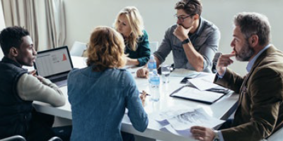 Industry professionals sitting at a conference table analyzing data and projects