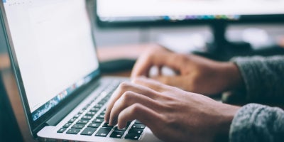 A student typing on a laptop editing a document.
