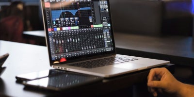 A student with a laptop using an audio editing software app.