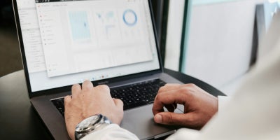 An employee working on graphs and data on a laptop.