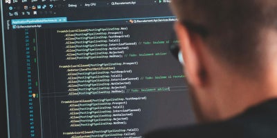 A male student working on code on a computer monitor.
