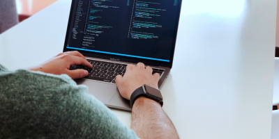 A male student working on code on a laptop.