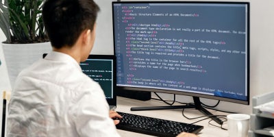 A male student coding on a computer monitor.