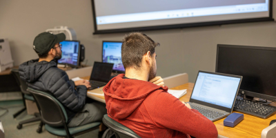 Two male students sitting down in a classroom listening to a lecture.