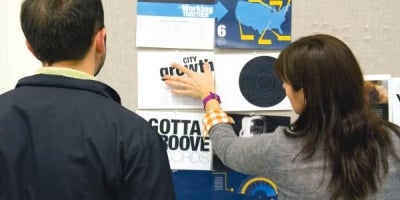 two people looking at a tackboard of pamphlets.