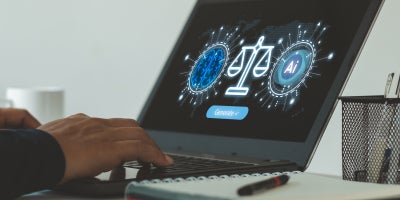 A student working on a computer displaying an illustration of AI and ethics.