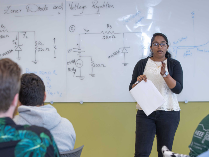 A professor teaching electrical engineering to a classroom full of students.
