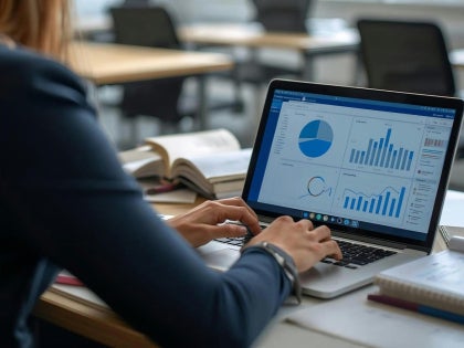 A female student working on data and graphs on a laptop.
