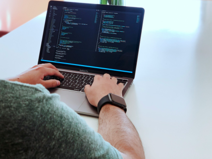 A male student working on code on a laptop.