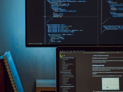 A laptop and a large computer monitor displaying code.