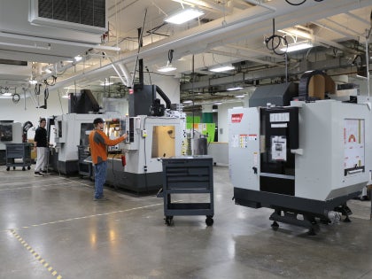 A wide shot of two students working lab equipment in a lab.