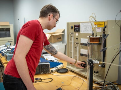 A student working on research equipment in a classroom.