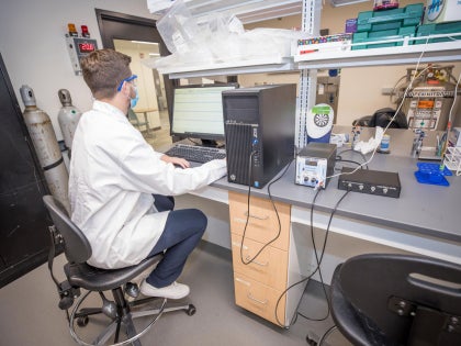 A research student typing on a computer in a lab.