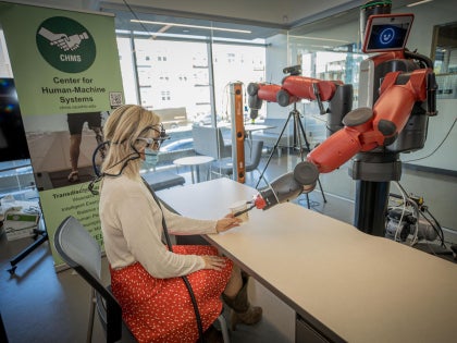 A student working on research with a robotic arm in a lab.