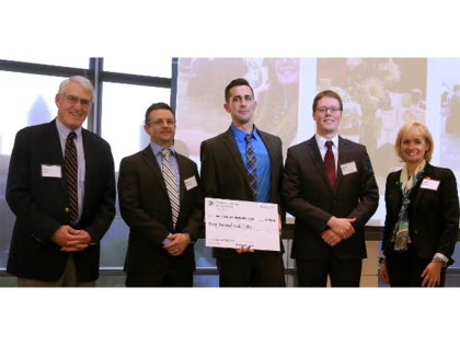 A group of students and professors posing for photo for winning competition.
