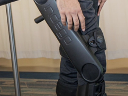 A person with a biomechanical leg walking on a treadmill in a lab.
