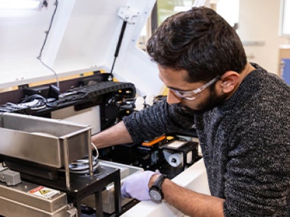 A student working with a machine in a lab.